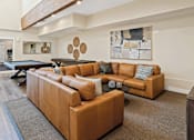 Thumbnail 3 of 10 - A brown leather couch with a blue pillow is in the center of a living room.