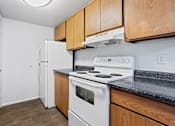Thumbnail 6 of 10 - A kitchen with a white stove and wooden cabinets.