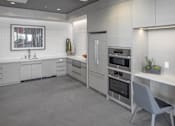 Thumbnail 22 of 35 - A modern kitchen with a grey floor and white cabinets.