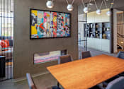 Thumbnail 21 of 35 - A large wooden table is surrounded by chairs in a room with a large painting on the wall.