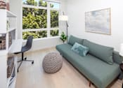 Thumbnail 15 of 35 - A living room with a green couch and a large window.