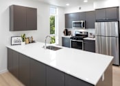 Thumbnail 5 of 35 - A modern kitchen with a white countertop and stainless steel appliances.