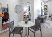Thumbnail 13 of 35 - A white table with two chairs and a vase of flowers sits in a room with a mirror and a coat rack.