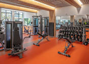 Thumbnail 32 of 35 - A gym with orange flooring and various exercise equipment.
