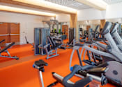 Thumbnail 2 of 35 - A gym with orange flooring and various exercise equipment.