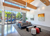 Thumbnail 20 of 35 - A modern living room with a couch, ottoman, and artwork on the wall.