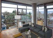 Thumbnail 2 of 29 - A grey couch with a glass table in front of a large window.