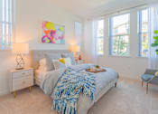 Thumbnail 24 of 28 - A bedroom with a bed, a chair, and a painting on the wall.