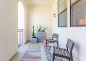 Thumbnail 25 of 28 - A balcony with a cactus, two chairs, and a table.