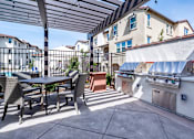 Thumbnail 1 of 21 - A patio with a table and chairs and a grill.