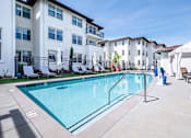 Thumbnail 2 of 21 - A swimming pool in front of a white apartment building.