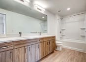 Thumbnail 16 of 21 - A modern bathroom with wooden cabinets and a white bathtub.
