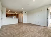 Thumbnail 15 of 28 - A large empty room with wooden flooring and white walls.
