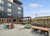 Thumbnail 23 of 48 - a patio with a table and chairs in front of a building