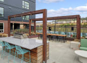 Thumbnail 24 of 48 - a patio with a bar and tables with chairs
