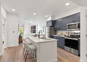 Thumbnail 1 of 30 - A kitchen with a white island and stainless steel appliances.