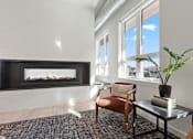 Thumbnail 15 of 30 - A living room with a fireplace and a chair.