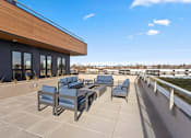Thumbnail 21 of 30 - A patio with blue chairs and a wooden building.