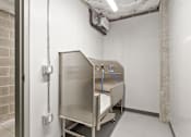 Thumbnail 27 of 30 - A metal cabinet with a blue hose is in a room with white walls.