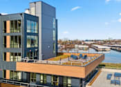 Thumbnail 22 of 30 - A modern building with a balcony overlooking a body of water.