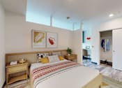 Thumbnail 8 of 32 - A bedroom with a bed, nightstand, and chair.