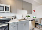 Thumbnail 4 of 32 - A modern kitchen with a microwave, oven, and a sink.