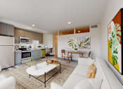 Thumbnail 1 of 32 - A modern kitchen with white appliances and a dining area with a white couch and a painting on the wall.