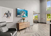 Thumbnail 10 of 33 - A living room with a black leather chair, a wooden dresser, and a painting on the wall.