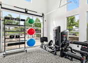 Thumbnail 31 of 48 - A gym with a variety of equipment including a weight rack, a rowing machine, and a stationary bike.
