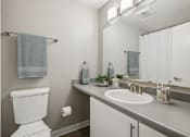 Thumbnail 11 of 22 - A white toilet is in a bathroom with a white sink and a mirror.