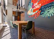 Thumbnail 11 of 28 - a dining area with a table and chairs and a mural on the wall