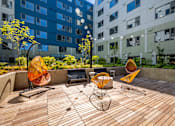 Thumbnail 22 of 28 - a patio area with chairs and a table in front of an apartment building