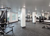 Thumbnail 32 of 34 - A gym with a variety of equipment including treadmills, weights, and benches.