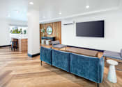 Thumbnail 3 of 34 - A blue couch sits in a room with a wooden floor and a white wall.