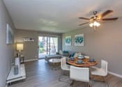 Thumbnail 2 of 14 - A dining room with a table set for two and a ceiling fan.