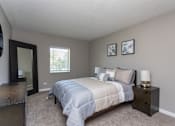 Thumbnail 3 of 14 - A bedroom with a bed, nightstand, and two pictures on the wall.