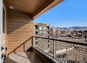 Thumbnail 8 of 22 - A balcony with a view of a parking lot and buildings.
