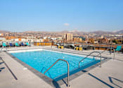 Thumbnail 22 of 22 - A swimming pool on a rooftop with mountains in the background.