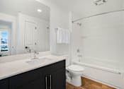 Thumbnail 6 of 22 - A white toilet sits next to a bathtub in a bathroom.