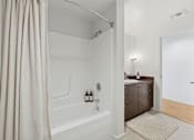 Thumbnail 7 of 18 - A bathroom with a white tub and a shower curtain.