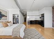 Thumbnail 1 of 18 - A studio with a large bed and a painting on the wall.