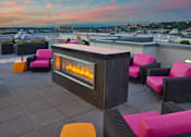 Thumbnail 7 of 7 - A modern outdoor seating area with a fireplace on a rooftop.