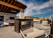 Thumbnail 6 of 7 - A rooftop patio with chairs and a bar.