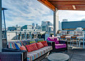 Thumbnail 1 of 7 - A colorful outdoor seating area with a view of the city skyline.