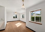 Thumbnail 20 of 21 - A room with a ceiling fan and a window with a view of a house.