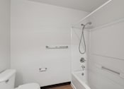 Thumbnail 16 of 21 - A white bathroom with a toilet, tub, and shower.