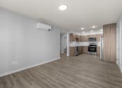 Thumbnail 8 of 30 - an empty living room and kitchen with wood flooring and white walls