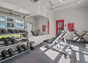 Thumbnail 7 of 21 - a gym with weights and mirrors at the district flats apartments in lenexa