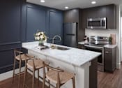 Thumbnail 1 of 35 - A kitchen with dark blue cabinets and a white marble countertop.