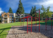 Thumbnail 1 of 30 - A red monkey bars set sits in the middle of a playground.